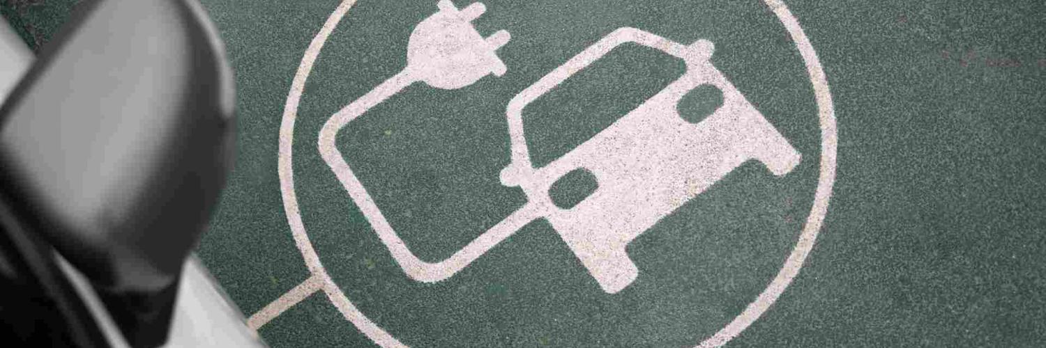 Símbolo de coche eléctrico con enchufe sobre asfalto